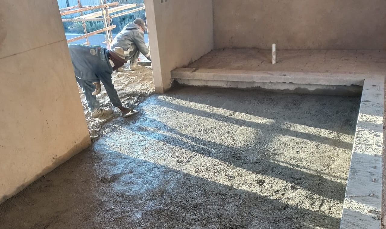 Synergy technician screeding a 20 mm SUNPERL perlite-cement layer level across a concrete slab