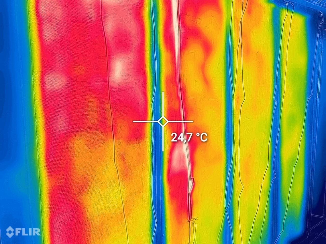 Thermal camera image during commissioning of carbon fibre wall heating panels, the spot reading showing 24.7 degrees Celsius on the film surface