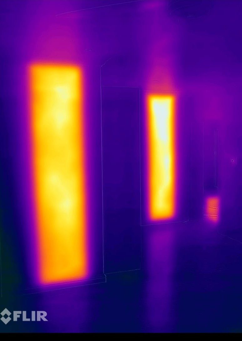 Thermal camera image of the same wall showing two carbon fibre heating panels radiating warmth into the room
